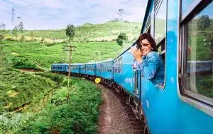 Happy smiling woman looks out from window traveling by train on most picturesque train road in Sri Lanka