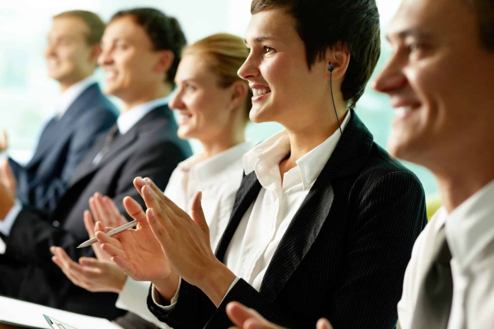 Business people sitting in a row and applauding.