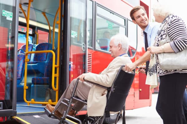 Driver Helping Elderly Senior Couple Board Bus Via Wheelchair Ramp - Tourism for All