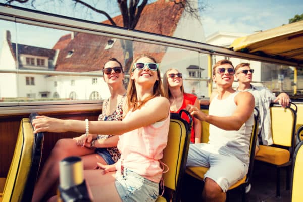 group of smiling friends traveling by tour bus