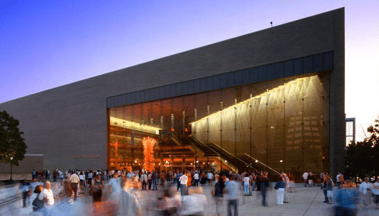 The outside of Abravanel Hall during sunset with lots of people gathered outside the building